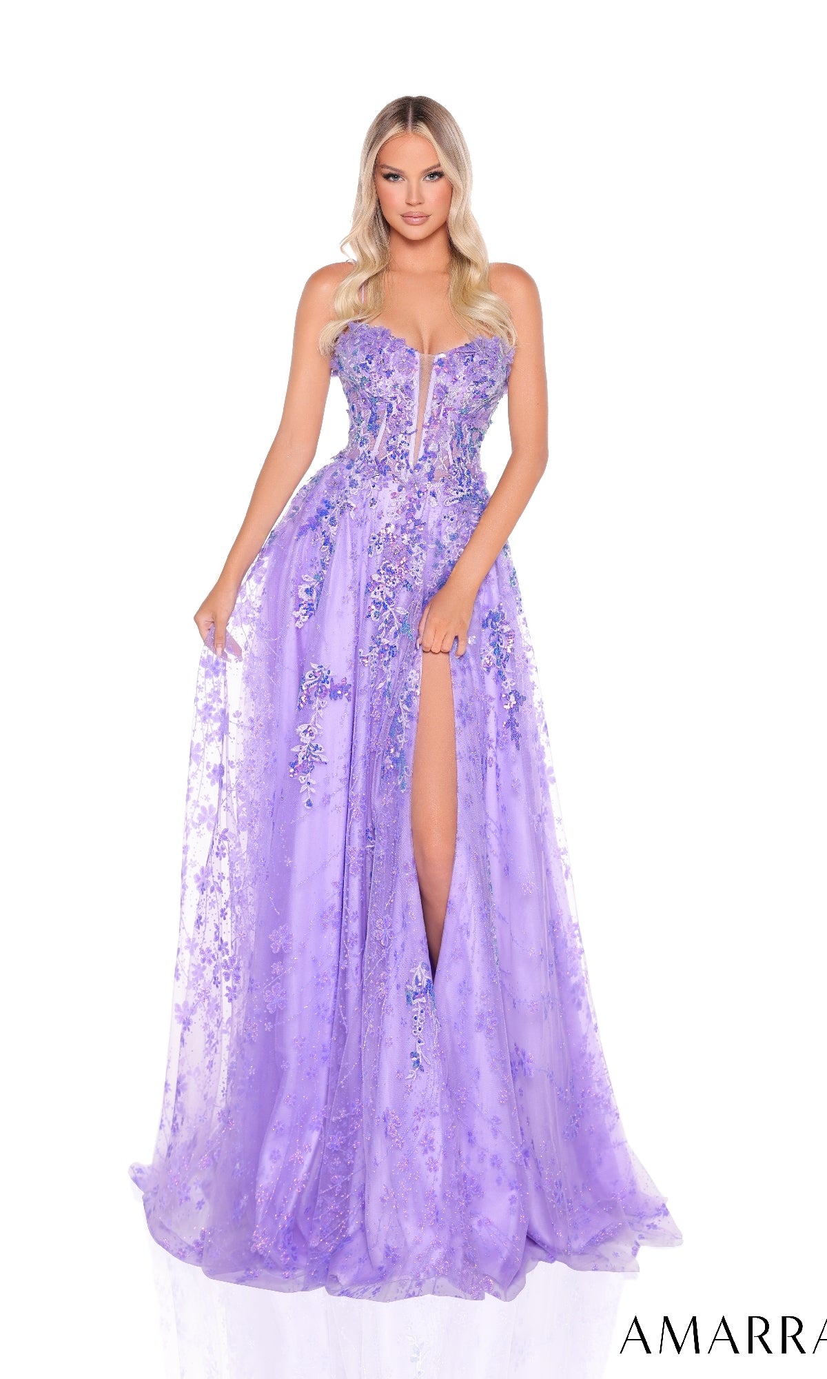 A woman stands against a white background wearing the Amarra 88315: a strapless, lavender A-line prom dress with 3D floral appliques, sheer details, and a thigh-high slit.